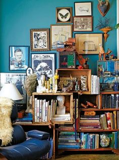 a living room filled with lots of books and pictures on the wall next to a chair