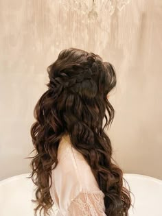 the back of a woman's head sitting in a bathtub with long curly hair