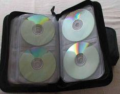 four cd's are in an open case on a bed