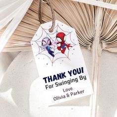 a spiderman thank you for swinging by gift tag hanging from a palm tree branch