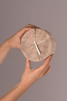 two hands holding a piece of wood with a cross on it and a clock in the middle