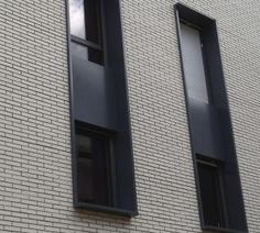 two windows on the side of a white brick building