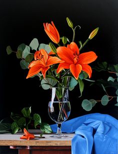 a vase filled with orange flowers sitting on top of a table next to a blue cloth