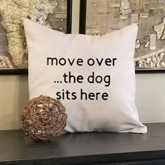 a pillow that says move over the dog sits here next to a ball on a dresser