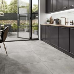 a modern kitchen with grey cabinets and marble counter tops, along with a dining room table