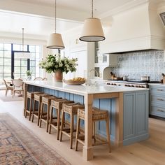 a large kitchen with blue cabinets and white counter tops, an island in the middle