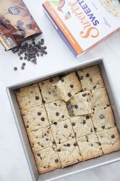 a pan filled with cookies and chocolate chips next to an open box of cereals