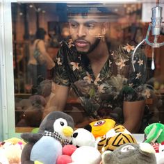 a man is looking through a window at stuffed animals and toys in front of him