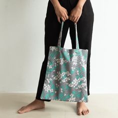 Carry your belongings in style with our White Blossoms Grey Tote Bag. The beautiful floral print adds a chic touch, while the spacious interior and pockets ensure all your necessities fit comfortably. It's a great option for a gift or to compliment any look. Trust us, your loved one will thank you!       Specs   Material: Cloth Quantity: 1 Pc Grey Tote Bag, Grey Tote Bags, Grey Tote, In Style, Blossom, Floral Print, Floral Prints, Tote Bag, Grey