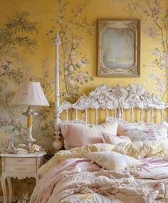 a bedroom with yellow walls and floral wallpaper, white bedding and pink comforter