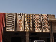 an old car is parked in front of some fabric hanging on the side of a building