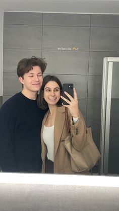 a man and woman taking a selfie in front of an elevator with their cell phone