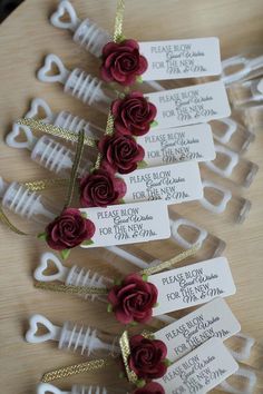 four wine bottle tags with red roses on them and some gold ribbons tied to them