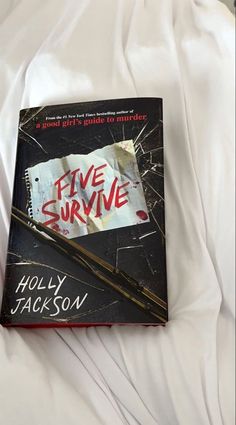 the book five survive is laying on top of a bed with white sheets and pillows