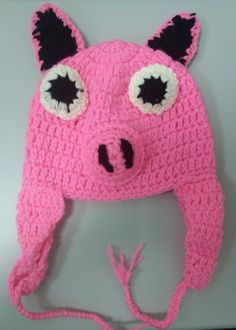 a crocheted pink hat with black ears and eyes