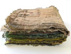 several pieces of cloth stacked on top of each other in different colors and patterns, all with frayed edges