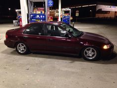 a maroon car is parked at a gas station