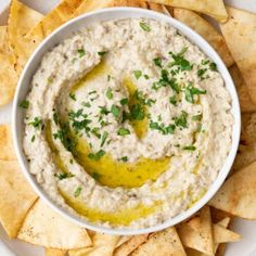 a white bowl filled with dip surrounded by tortilla chips