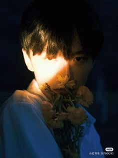 a young man holding flowers in his hand with the light shining on him from behind