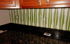 a kitchen with green and white striped wall paper on the backsplash, wood cabinets