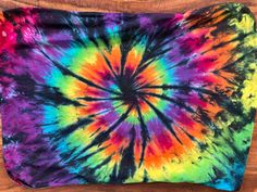 a colorful tie - dyed pillow sitting on top of a wooden table