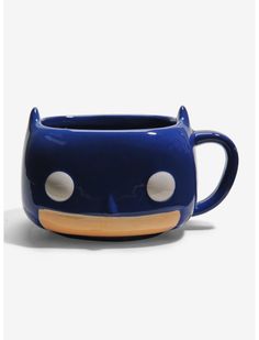 a blue ceramic cup with white polka dots on the side and a cat's head