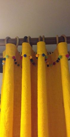 the curtains are yellow and have pom - poms on them