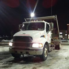 a white tow truck is parked in the snow