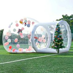 an inflatable christmas tree is on the grass next to two large blow up balls