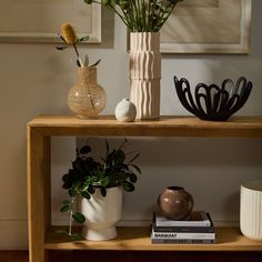 two vases with flowers are sitting on a shelf next to books and other decorative items