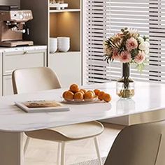 a white table with some oranges on top of it in front of a window