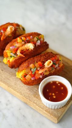 three fried food items on a cutting board with dipping sauce