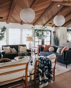 a living room with couches, chairs and lamps hanging from the rafter ceiling