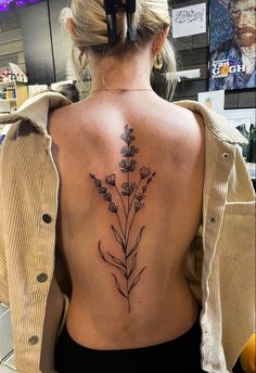 a woman's back with a flower tattoo on her left side ribcage