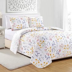 a bed with white sheets and colorful flowers on it