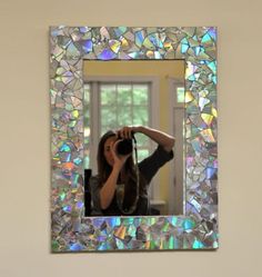 a woman taking a photo with her camera in front of a mirror that has iridescents on it