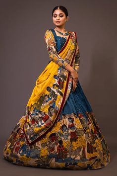 Blue base attached cancan lehenga with humans and animals kalamkari hand painted patterns and embroidery. Paired with padded blue blouse embroidered with glass beads and yellow printed dupatta with contrast border. - Aza Fashions Coat Dresses For Women Traditional, Kalamkari Lehenga Designs Latest, Yellow And Blue Lehenga, Kalamkari Family Outfits, Ikkat Half Saree Designs, Penkalamkari Lehanga, Pen Kalamkari Lehangas, Kalamkari Lehengas, Kalamkari Lehenga Designs