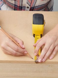 a woman is using a measuring tape to measure the width of a piece of wood