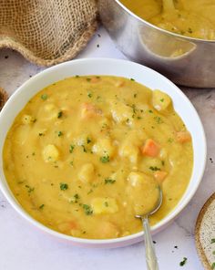 there is a bowl of soup on the table next to two spoons and bread