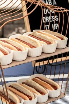 there are many hotdogs on the three tiered rack with buns in them