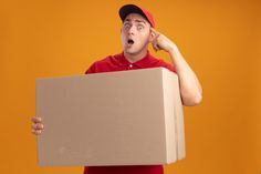 a man in a red shirt is holding a cardboard box and making a surprised face