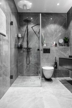 a modern bathroom with grey marble walls and flooring, including a walk in shower