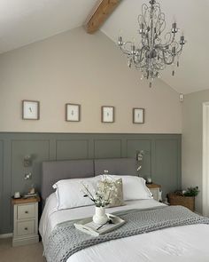 a white bed sitting under a chandelier in a bedroom