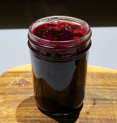 a jar filled with red liquid sitting on top of a wooden cutting board