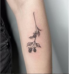 a small black and white flower tattoo on the left arm, with berries growing from it