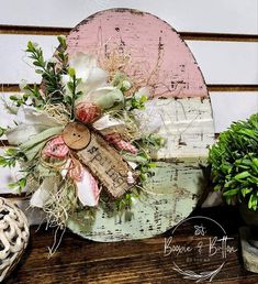 a wooden sign with flowers on it sitting next to potted plants and other decorations