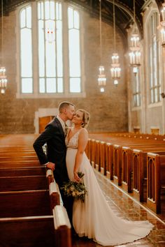 a bride and groom kissing in front of pews