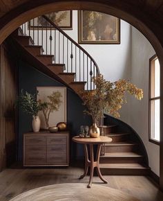 an entryway with stairs and vases on the table