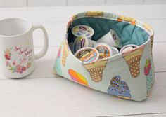 a cup holder with ice cream and buttons in it next to a mug on a table