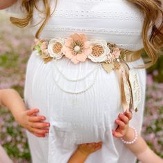 a pregnant woman is holding her child's belly with flowers on the bottom and side